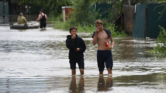 俄罗斯民众在齐腰深洪水中悠哉吃零食